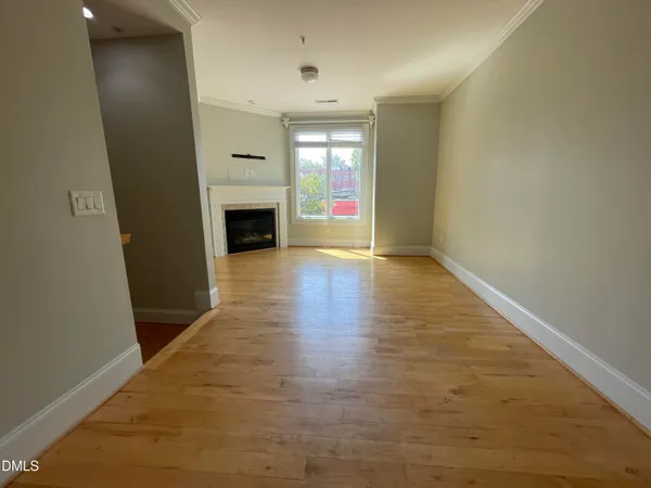 an empty room with wooden floor fireplace and windows