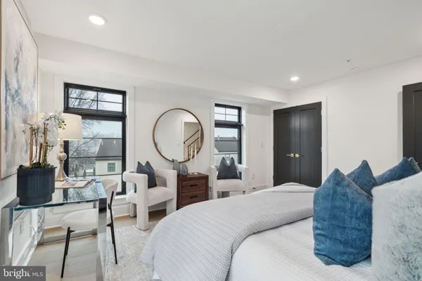 a bedroom with bed a mirror and a large window