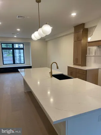 a large kitchen with stainless steel appliances a large counter top a chandelier and a wooden floor