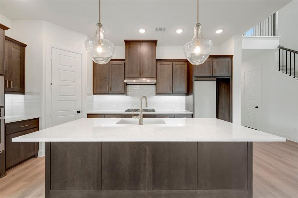 1908 Cola Drive Van Alstyne, TX 75495 - Photo 15 of 29 Kitchen featuring a large island with a light-toned countertop, dark wood cabinetry, and pendant lighting