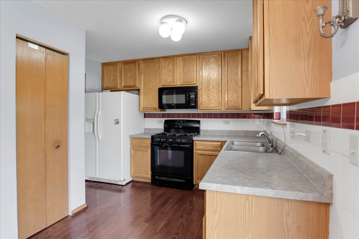 2029 Ridgemoor Drive Plainfield, IL 60586 - Photo 9 of 26 a kitchen with granite countertop stainless steel appliances a stove top oven a refrigerator and a sink with wooden floor