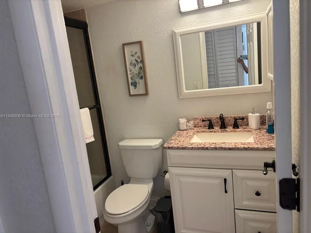 a bathroom with a granite countertop toilet and a sink