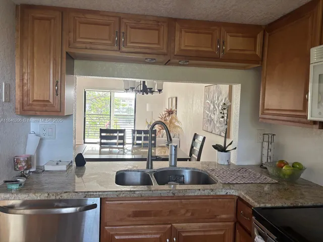 a kitchen with stainless steel appliances granite countertop a sink and a stove next to a window