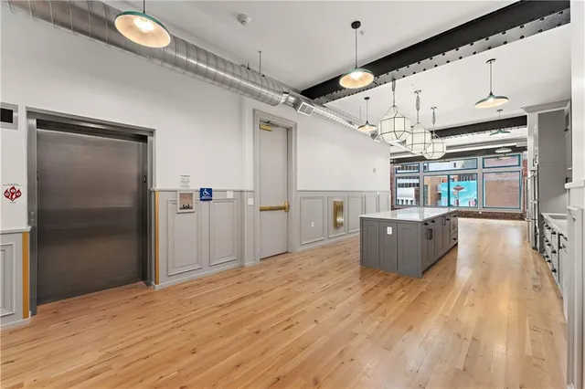 a kitchen with stainless steel appliances kitchen island a refrigerator and a wooden floor