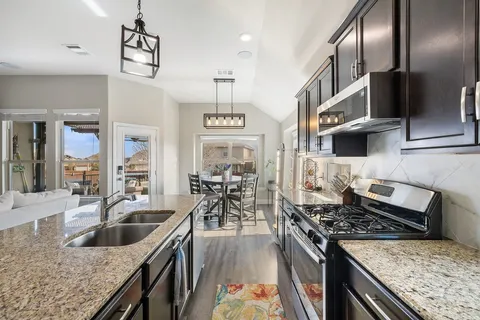 a kitchen with stainless steel appliances granite countertop a sink stove and refrigerator