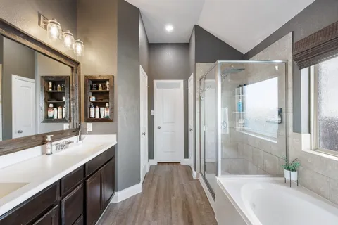 a spacious bathroom with a double vanity sink a large mirror and shower