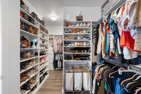a view of walk in closet with clothes and shoes