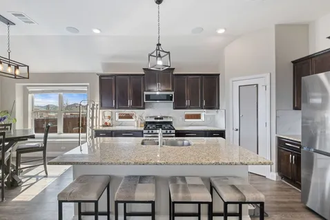 a kitchen with granite countertop stainless steel appliances cabinets a dining table and a chandelier