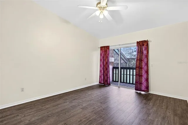 an empty room with wooden floor fan and windows