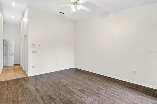 an empty room with wooden floor and fan