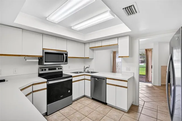 a kitchen with white cabinets stainless steel appliances and a sink