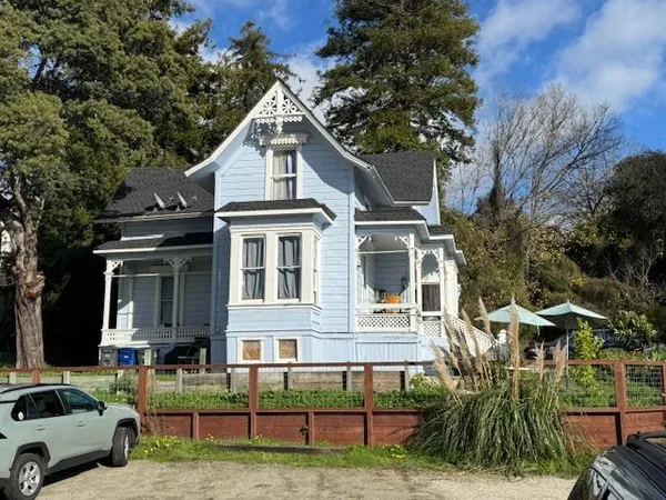 a view of house with yard outdoor seating and covered with trees