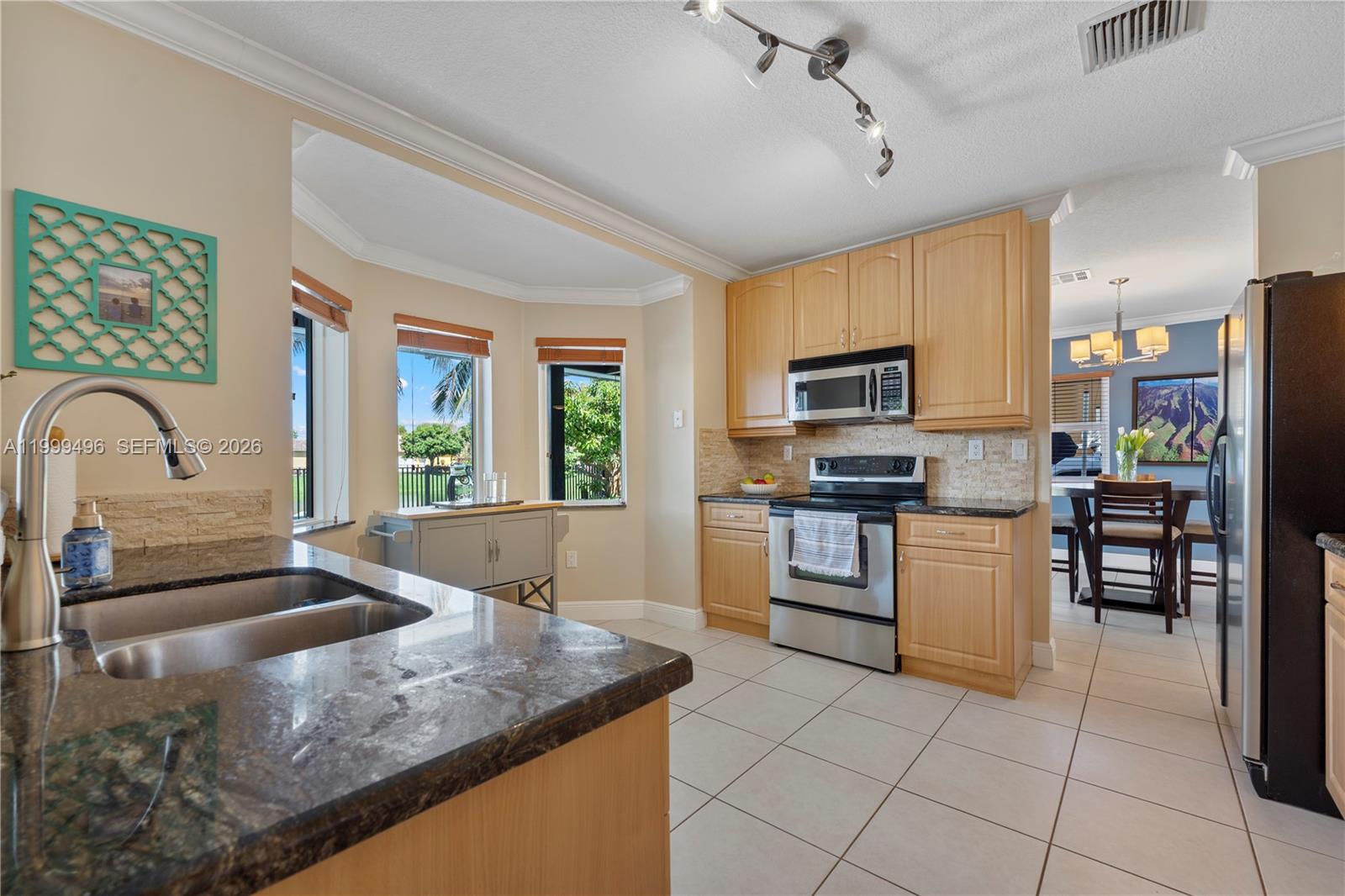 20918 Southwest 89th Path Cutler Bay, FL 33189 - Photo 15 of 47 a kitchen with stainless steel appliances granite countertop a stove top oven a sink dishwasher a dining table and chairs with wooden floor