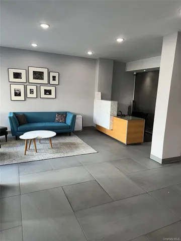 a living room with furniture a flat screen tv and a refrigerator