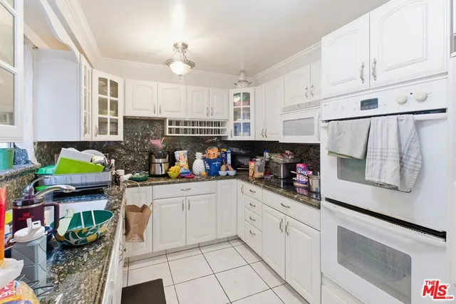 a kitchen with kitchen island granite countertop a stove a sink and white cabinets