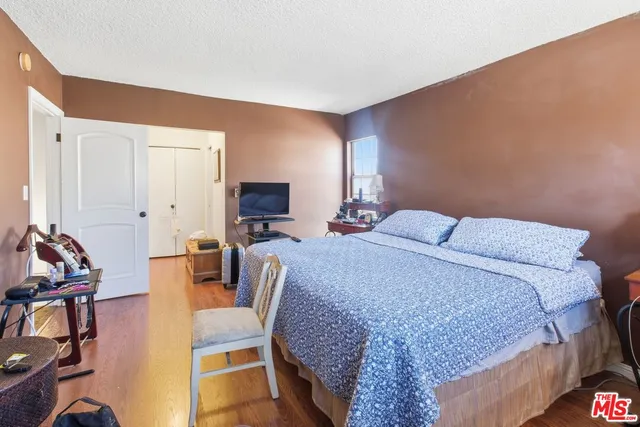 a bedroom with a bed a couch and a lamp on the dresser