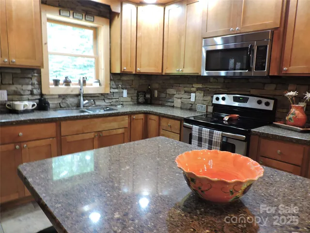a kitchen with stainless steel appliances granite countertop a sink a microwave and cabinets