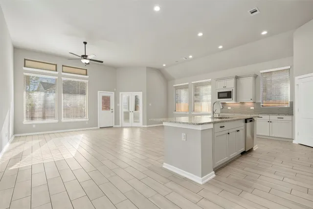 a large kitchen with granite countertop a white stove top oven and white cabinets