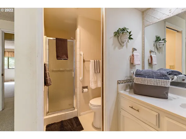 a bathroom with a granite countertop sink a toilet a glass door a shower