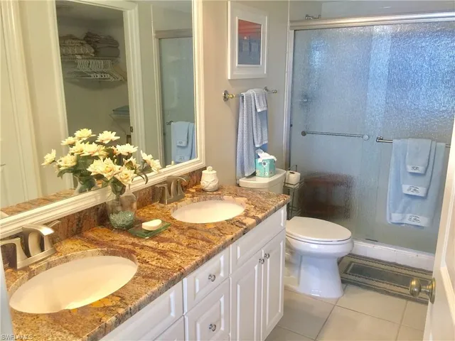 a bathroom with a granite countertop sink a toilet a mirror and shower