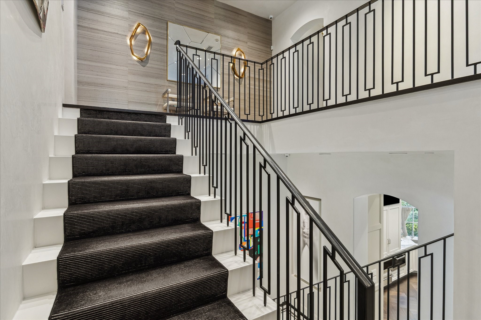 220 Merrie Way Lane Houston, TX 77024 - Photo 30 of 50 A custom runner and modern black railings guide you up the Segreto-plastered stairway, where the landing is finished with patterned designer wallpaper and paired gold sconces.