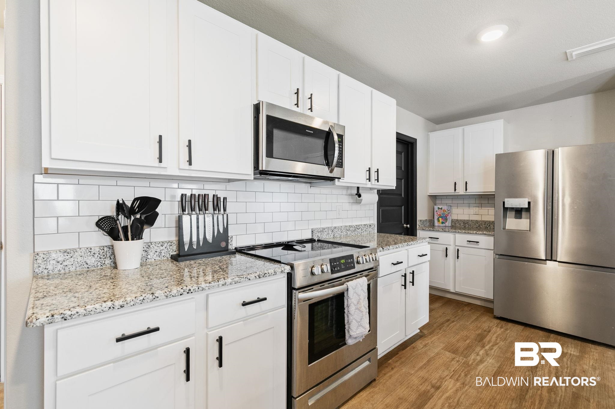 32234 Calder Court Daphne, AL 36527 - Photo 13 of 32 Kitchen with stainless steel appliances, white cabinets, light stone counters, light wood finished floors, and tasteful backsplash