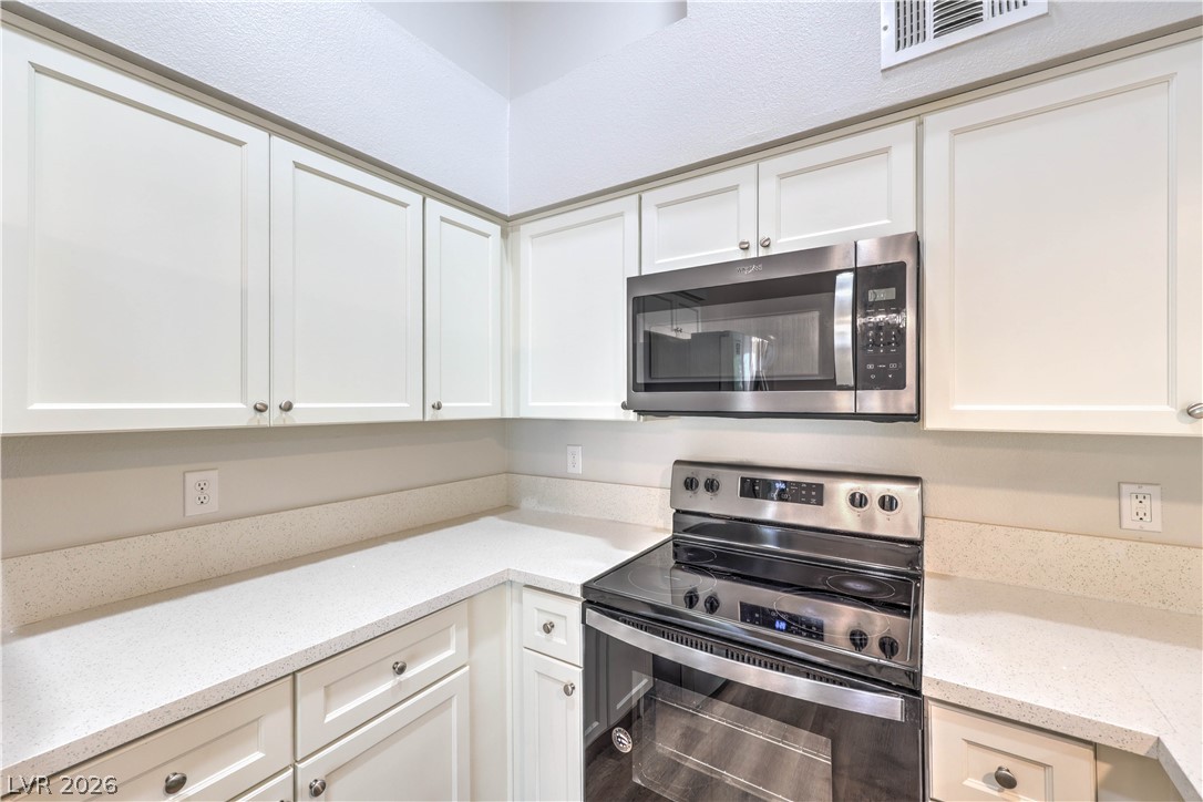 1575 West Warm Springs Road, Unit 322 Henderson, NV 89014 - Photo 11 of 25 This modern kitchen features crisp white cabinetry and sleek countertops, perfect for culinary endeavors.