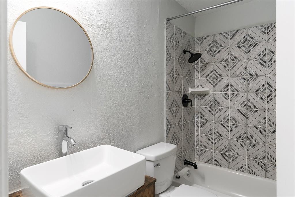 1330 Fordham Road Dallas, TX 75216 - Photo 23 of 37 Bathroom featuring a white rectangular vessel sink with chrome faucet, a round wood-framed mirror, and patterned shower tiling