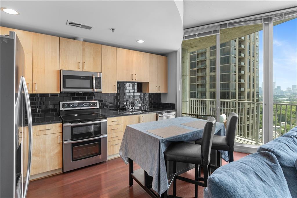 361 17th Street Northwest, Unit 2115 Atlanta, GA 30363 - Photo 8 of 24 a kitchen with stainless steel appliances granite countertop a stove a refrigerator a kitchen island a table and chairs