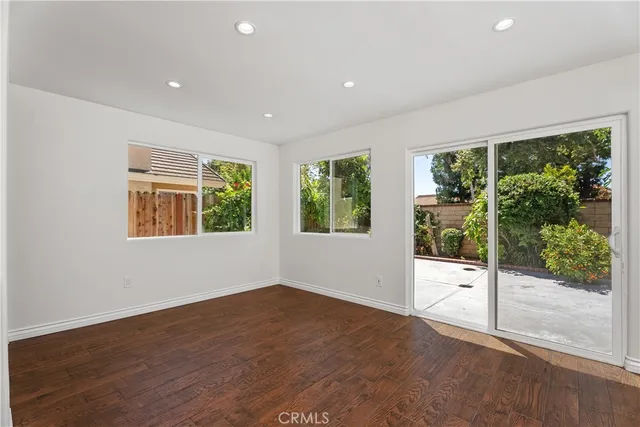 a view of an empty room with wooden floor and windows
