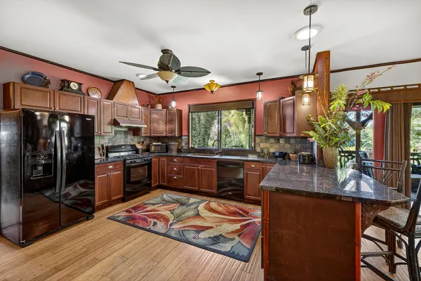 a kitchen with stainless steel appliances granite countertop a refrigerator a stove and a wooden floors