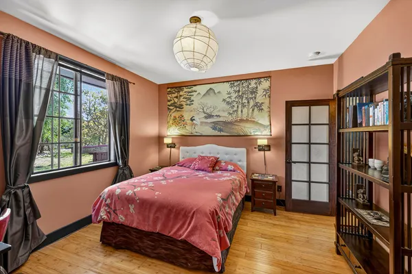 a bedroom with a bed a dresser and a large window