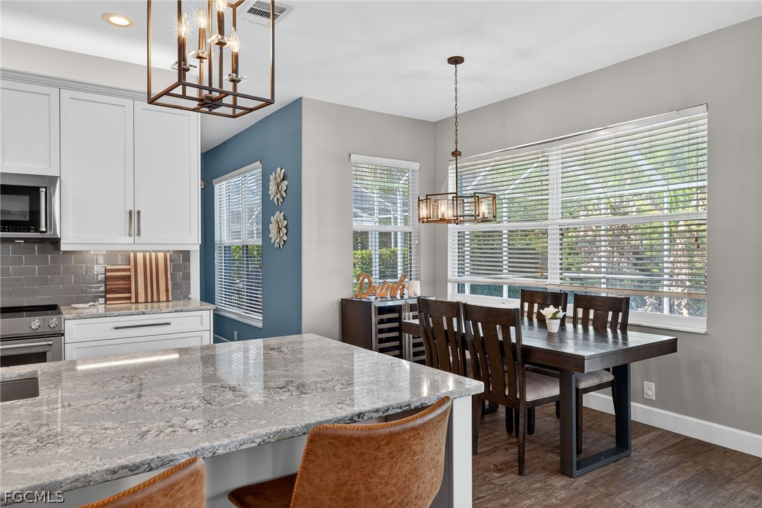 22866 Forest Ridge Drive Estero, FL 33928 - Photo 7 of 38 a dining room with wooden floor a chandelier a wooden table and chairs