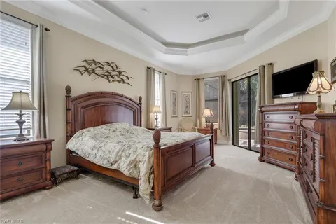 a bedroom with a bed and a flat tv screen on dresser
