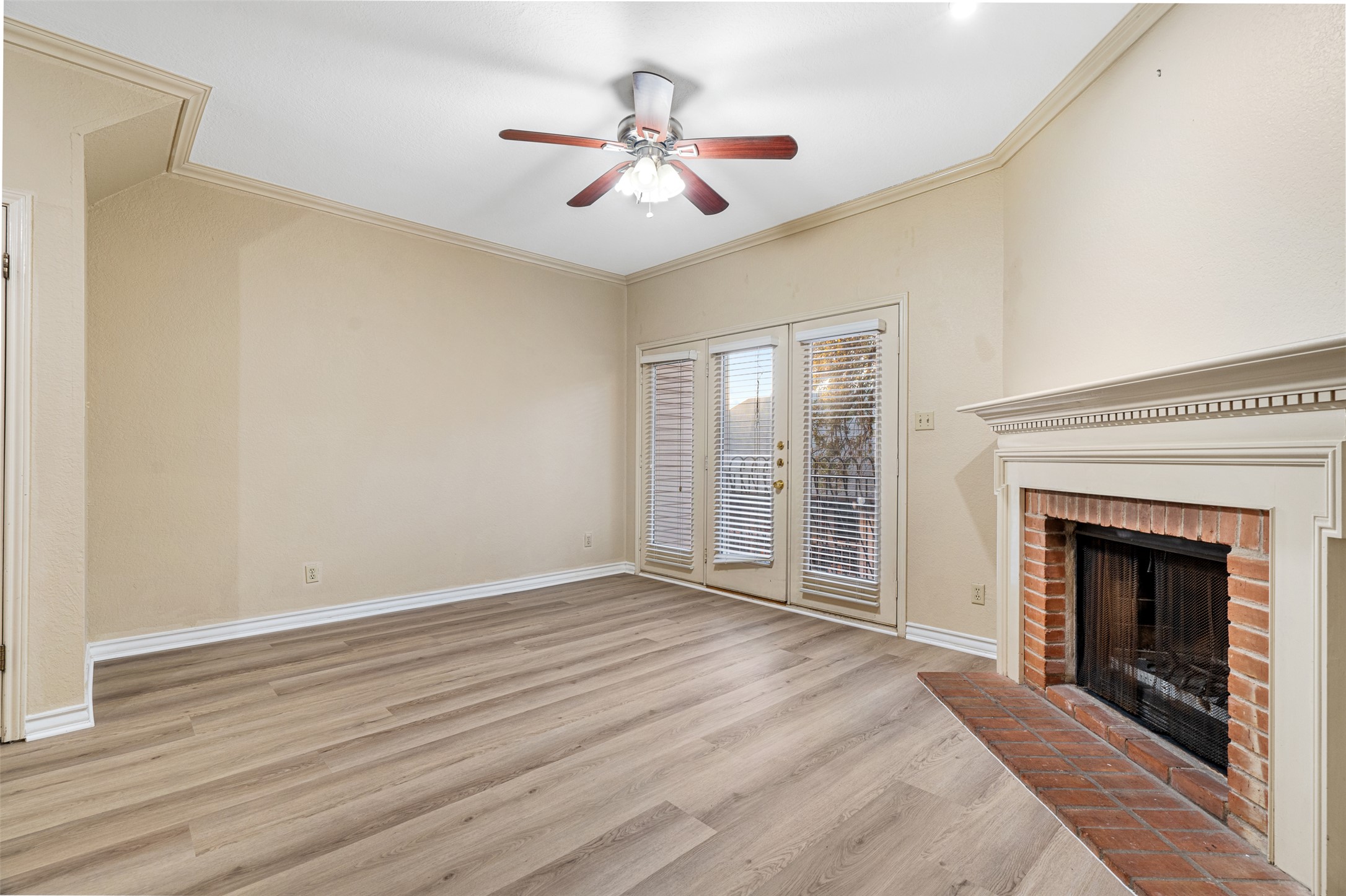 2408 Enfield Road, Unit 211 Austin, TX 78703 - Photo 7 of 26 Unfurnished living room with ornamental molding, a brick fireplace, light wood-style floors, and a ceiling fan