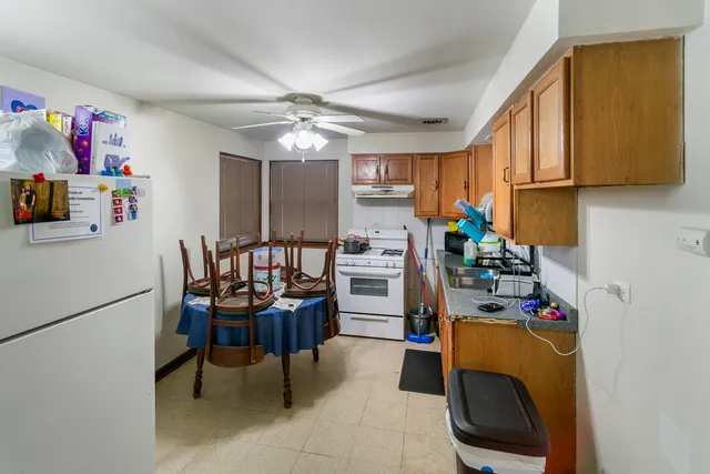 a kitchen with stainless steel appliances granite countertop a dining table chairs refrigerator and sink