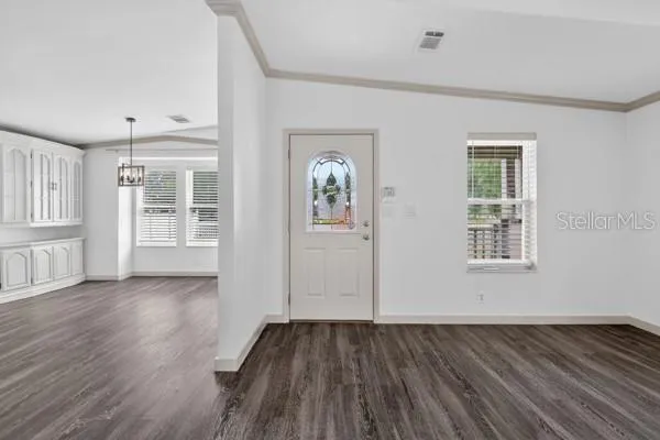a view of an empty room with wooden floor and a ceiling fan