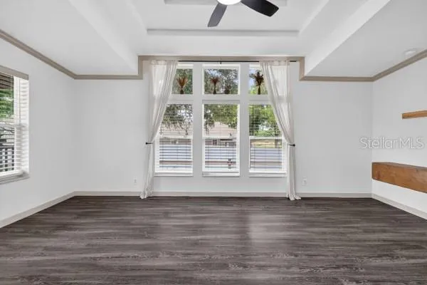 an empty room with wooden floor chandelier fan and windows