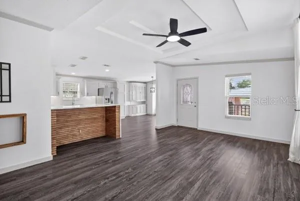 a view of a livingroom with a kitchen a ceiling fan wooden floor and a ceiling fan