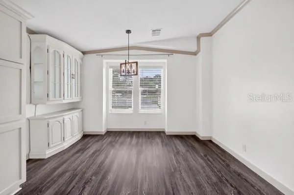 a view of an empty room with wooden floor fridge and a window