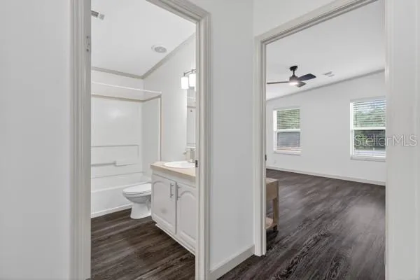 a view of empty room with wooden floor and fan