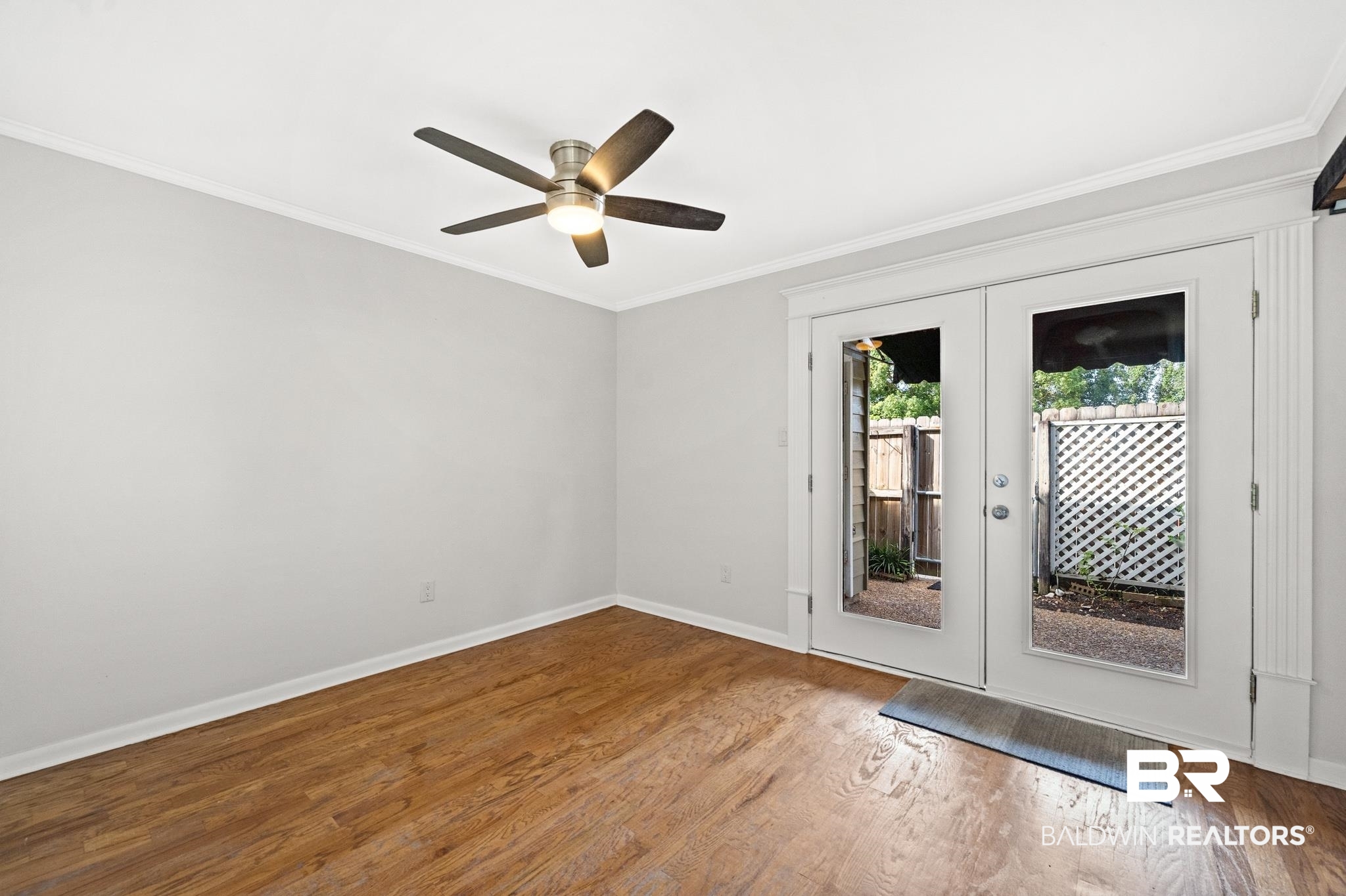 2901 Grant Street, Unit 802 Mobile, AL 36606 - Photo 11 of 37 Empty room featuring ceiling fan, french doors, hardwood / wood-style flooring, and ornamental molding