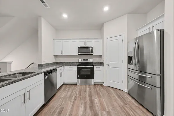 a kitchen with a refrigerator stove and white cabinets