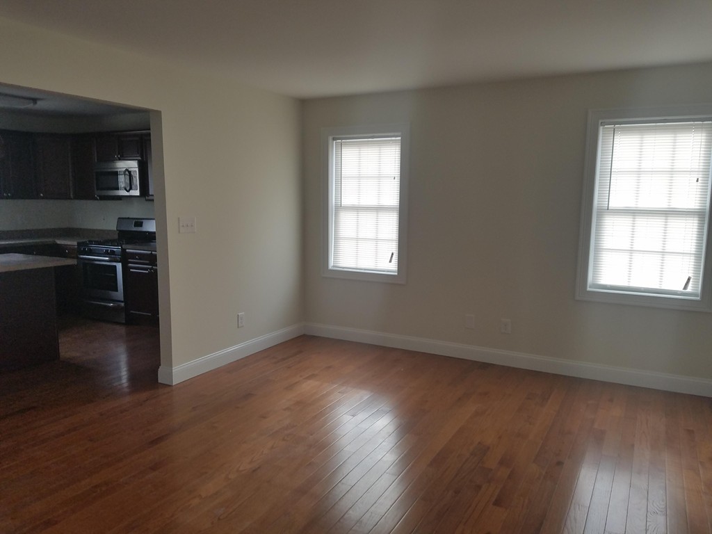 23 Beech Street Springfield, MA 01105 - Photo 6 of 10 an empty room with wooden floor cabinet and windows