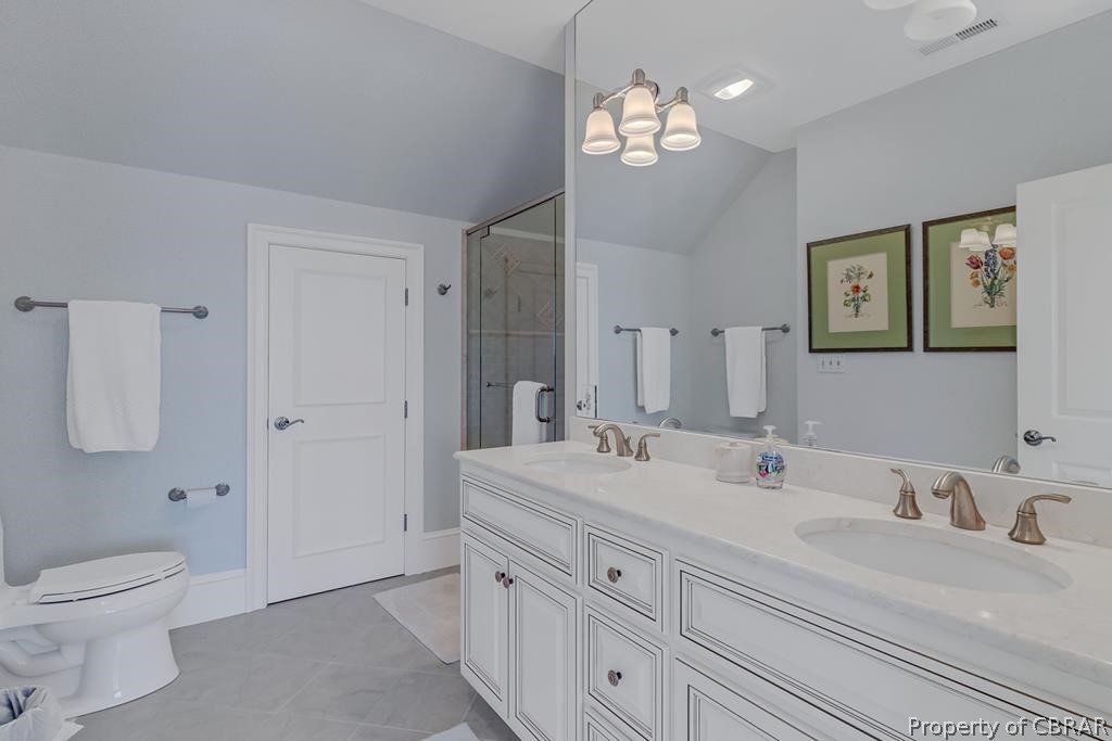 2055 Ditchley Road Kilmarnock, VA 22482 - Photo 40 of 48 Bathroom featuring oversized vanity, double sink, vaulted ceiling, tile floors, and toilet