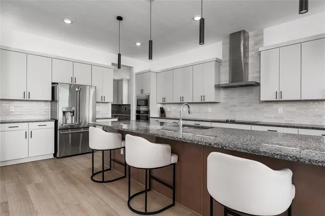 a kitchen with stainless steel appliances granite countertop a stove a sink a table and chairs with wooden floor