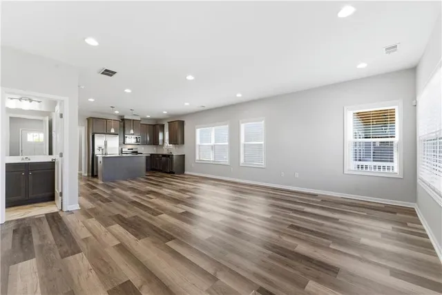 a view of kitchen and empty room with wooden floor