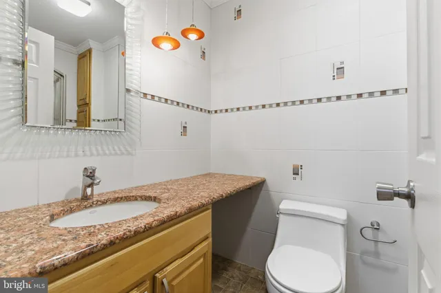 a bathroom with a granite countertop toilet sink and mirror