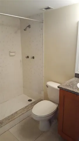 a bathroom with a granite countertop toilet a sink and shower