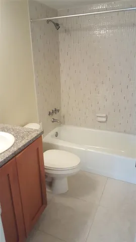 a bathroom with a granite countertop bathtub shower sink vanity and toilet